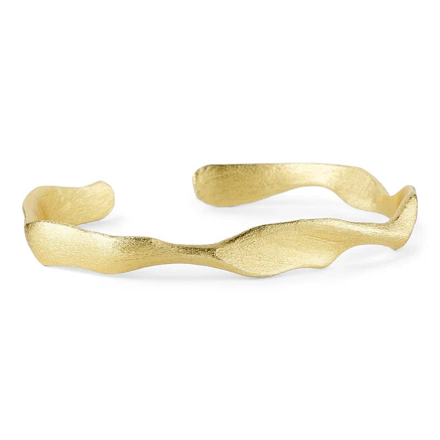 The Dora Bangle by Watermelon Tropical is a handmade gold cuff bracelet featuring a textured, wavy design with uneven, organic edges and a matte finish for modern, chunky appeal.