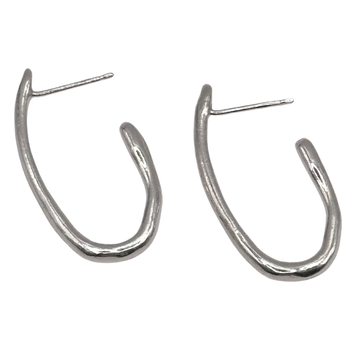 The Drop Organic Hoop Earrings by Inó Jewellery are handmade matte silver earrings with posts for pierced ears, featuring an irregular shape and rustic, hand-formed look—perfect for your unique collection.