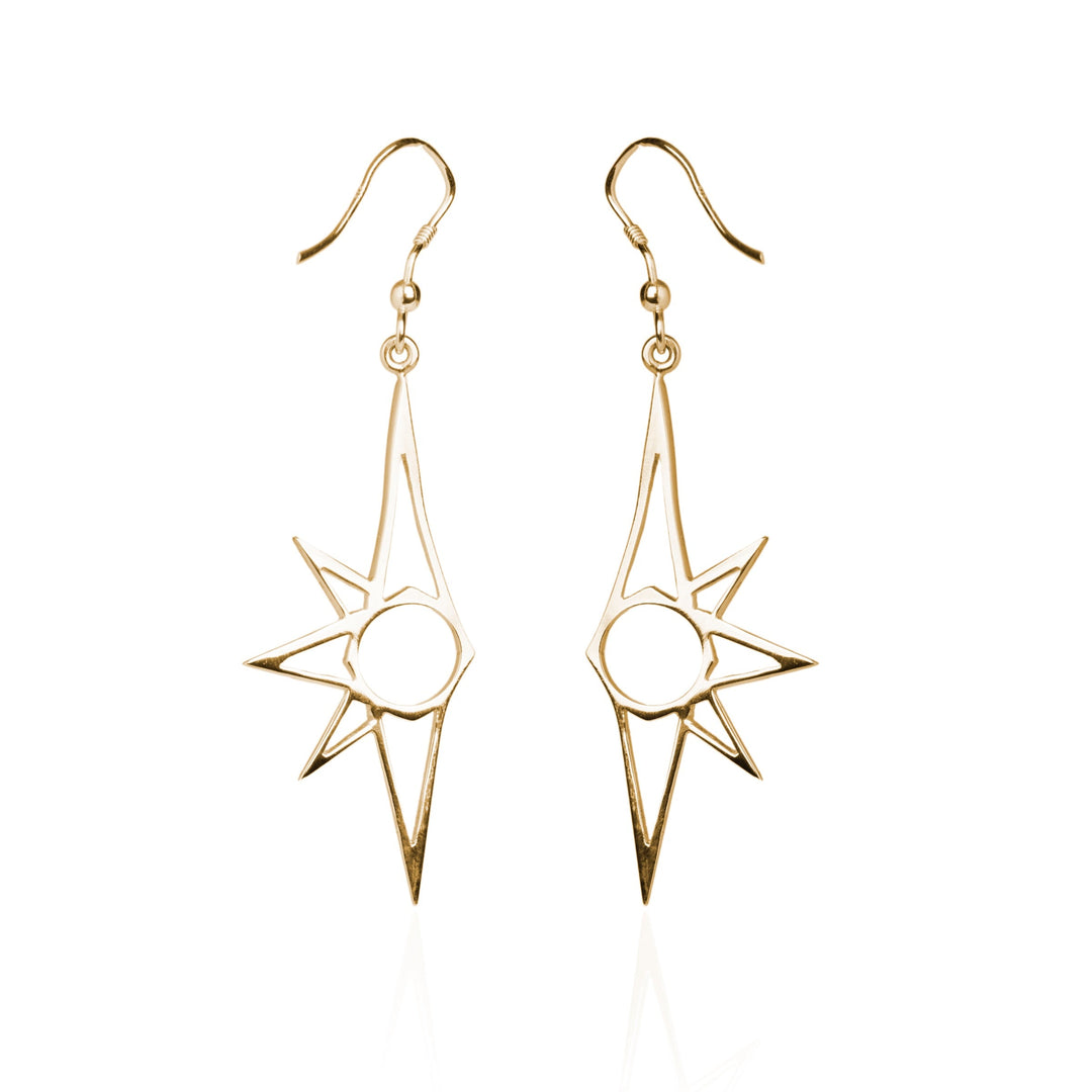 A pair of gold earrings featuring an abstract sunburst design, these Starlight Earrings by Cosmic Boulevard boast a central circular element with several pointed rays extending outward. The dangle-style earrings, hanging from delicate hooks, exhibit a minimalist and modern flair while evoking the charm of Starlight.