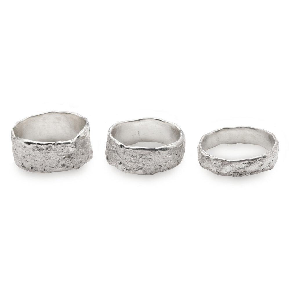 Three wide, sterling silver **Elements Ring Wide** by **Abbie Dixon** with a rough, textured finish are displayed side by side. Each ring has an irregular, organic shape, giving a uniquely handcrafted appearance. The rings vary slightly in size and texture against a plain white background.