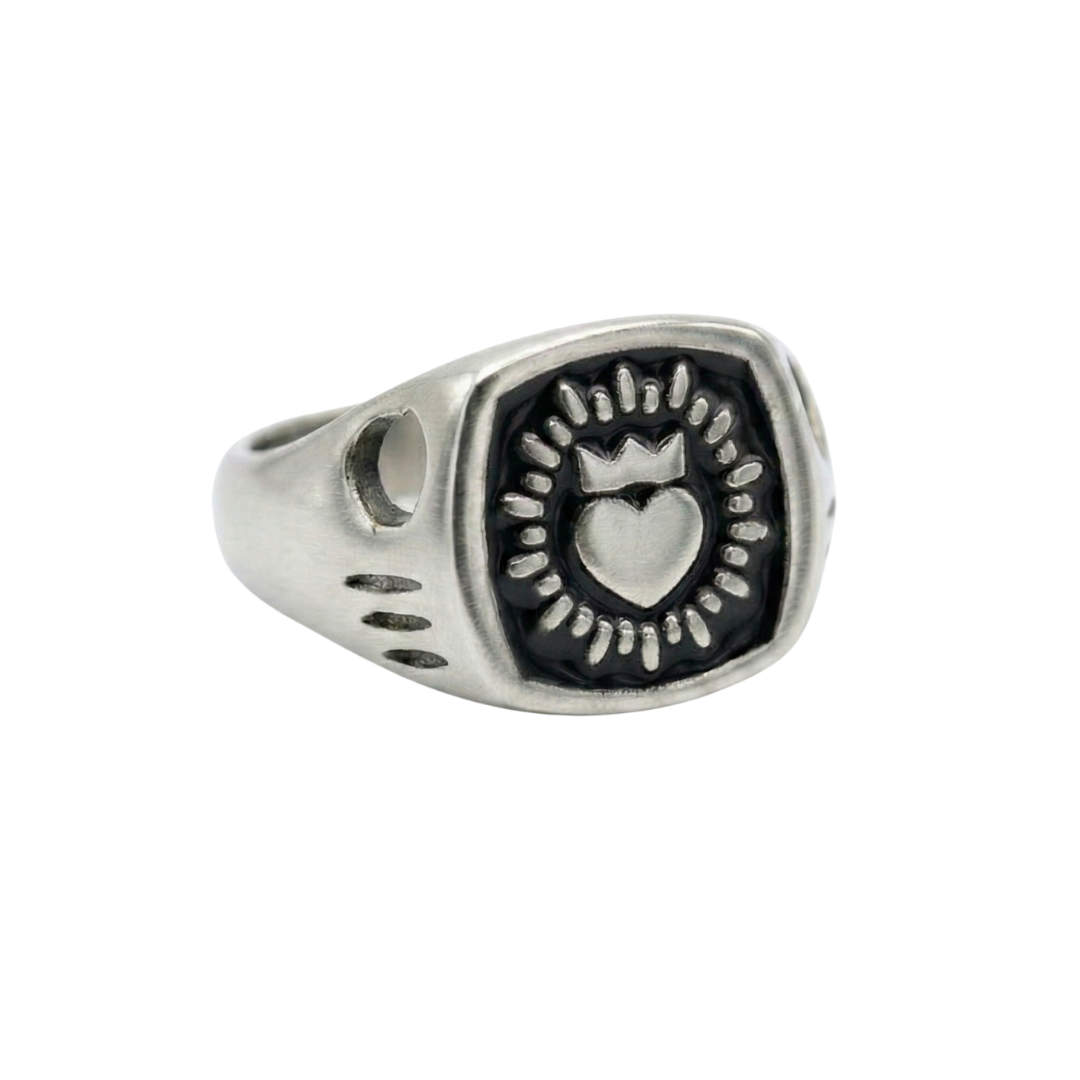 The Collective Dublin’s Enamel Keith Haring Inspired Claddagh Ring features a crowned heart and circular motif on a rectangular face with etched band details—a handmade piece with timeless Dublin style.