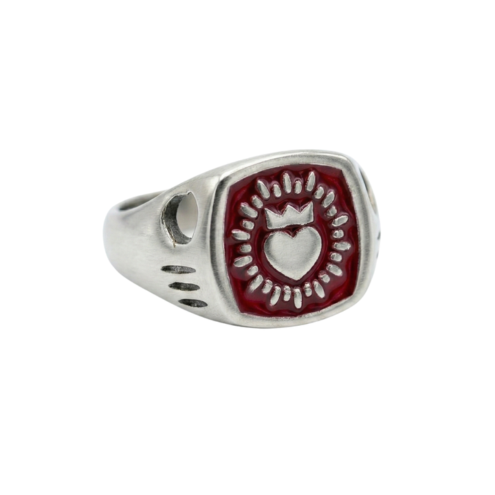 The Collective Dublin’s Enamel Keith Haring Inspired Claddagh Ring features a red rectangular face with a raised crowned heart design and radiating lines—a unique handmade piece of Dublin jewelry.