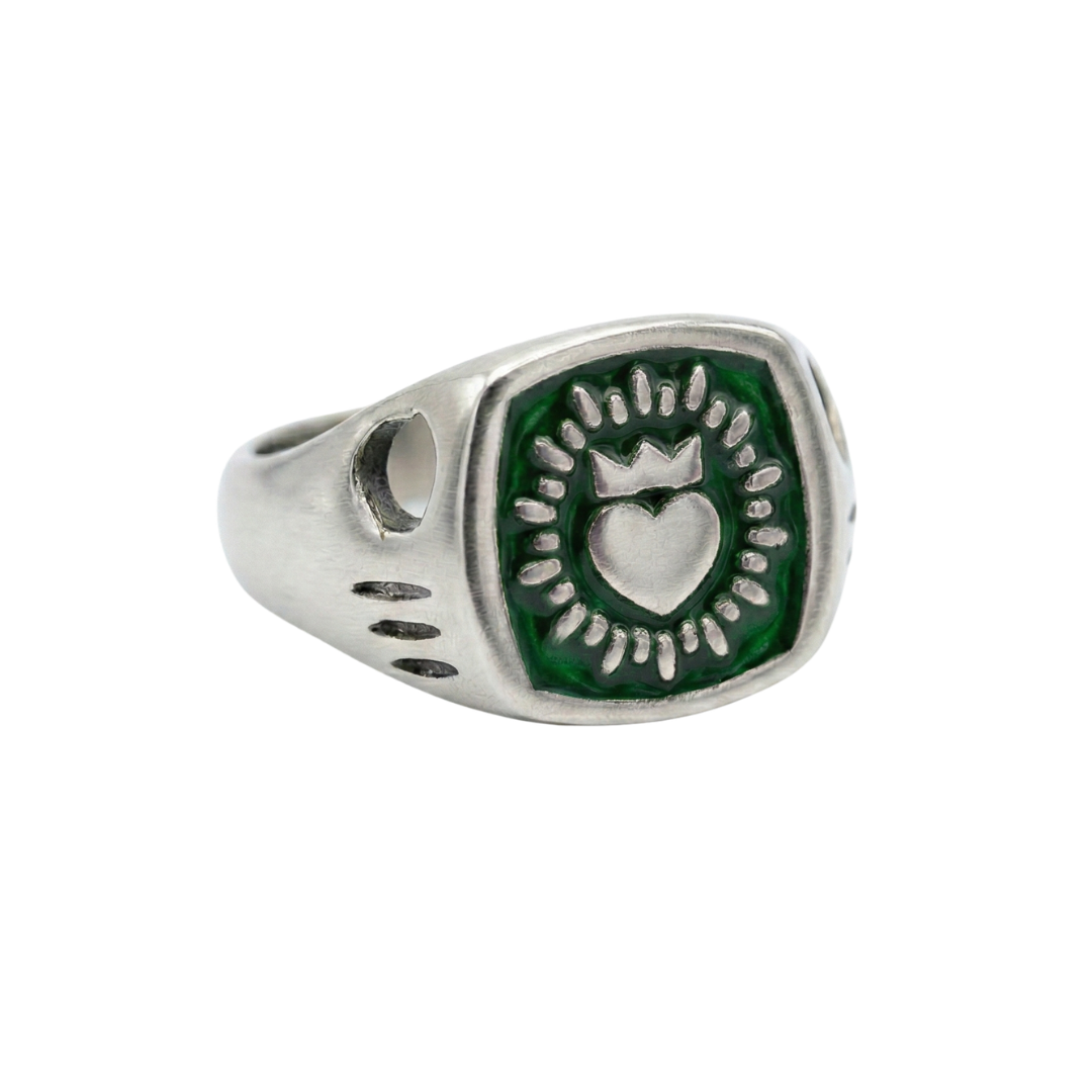 The Collective Dublin's Enamel Keith Haring Inspired Claddagh Ring features a green hexagonal face with an engraved crowned heart and sunburst pattern, set on a handmade signet band with simple grooves.