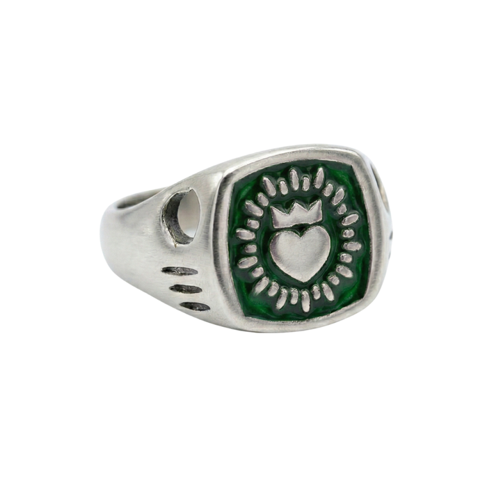 The Collective Dublin's Enamel Keith Haring Inspired Claddagh Ring features a green hexagonal face with an engraved crowned heart and sunburst pattern, set on a handmade signet band with simple grooves.