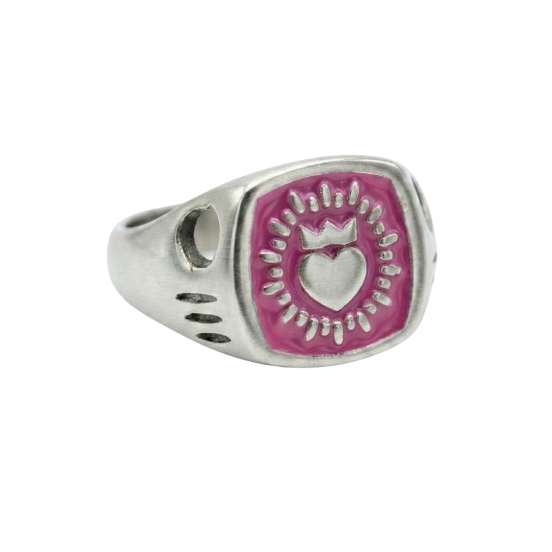 The Collective Dublin’s Enamel Keith Haring Inspired Claddagh Ring features a pink, hexagonal face with heart and crown motifs, surrounded by decorative marks and a band detailed with cutouts and dots for handmade Dublin charm.