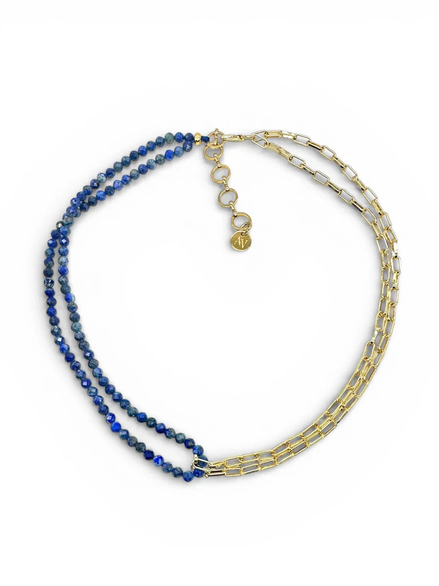 The Ethere Lapis Necklace by Aria V is a handmade Irish choker with dual strands: blue lapis lazuli-like beads and gold chain links, finished with an adjustable gold clasp and circular charm.