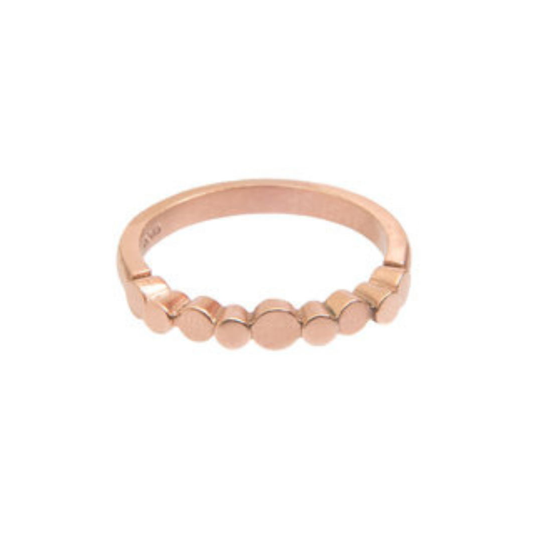 The Miriam Wade Flow Pebble Ring in 9ct rose gold features a stackable band adorned with a row of small, round flat discs along the front, shown against a white background.