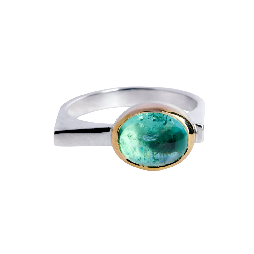 The Madeleine Forest Aura ring showcases a striking oval green tourmaline in a 9ct yellow gold bezel on a sleek sterling silver band, set against a white background.