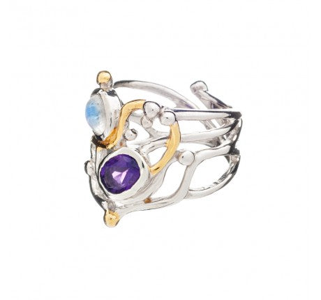 A unique, intricate Seaweed Ring in various gemstones made of sterling silver with gold vermeil accents by Gallardo & Blaine Designs. It features two gemstones: a blue one on top and a purple one below, set within an elaborate design of intertwining metal and small spherical details. The background is plain white.