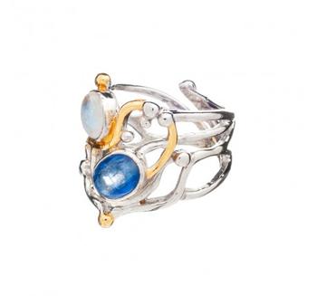 The Seaweed Ring in various gemstones, crafted from sterling silver, showcases an intricate, intertwined design with two prominent gemstones: a larger blue stone set lower and a smaller white stone set higher. Gold vermeil accents highlight parts of the design, giving it a unique, artistic look by Gallardo & Blaine Designs.