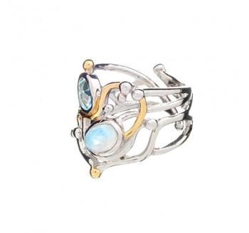 A silver statement ring featuring an intricate, open metalwork design, crafted from sterling silver and adorned with two large gemstones—one blue and one iridescent—as well as small gold vermeil embellishments. This exquisite piece is reminiscent of the ocean, earning it the name Seaweed Ring in various gemstones by Gallardo & Blaine Designs.