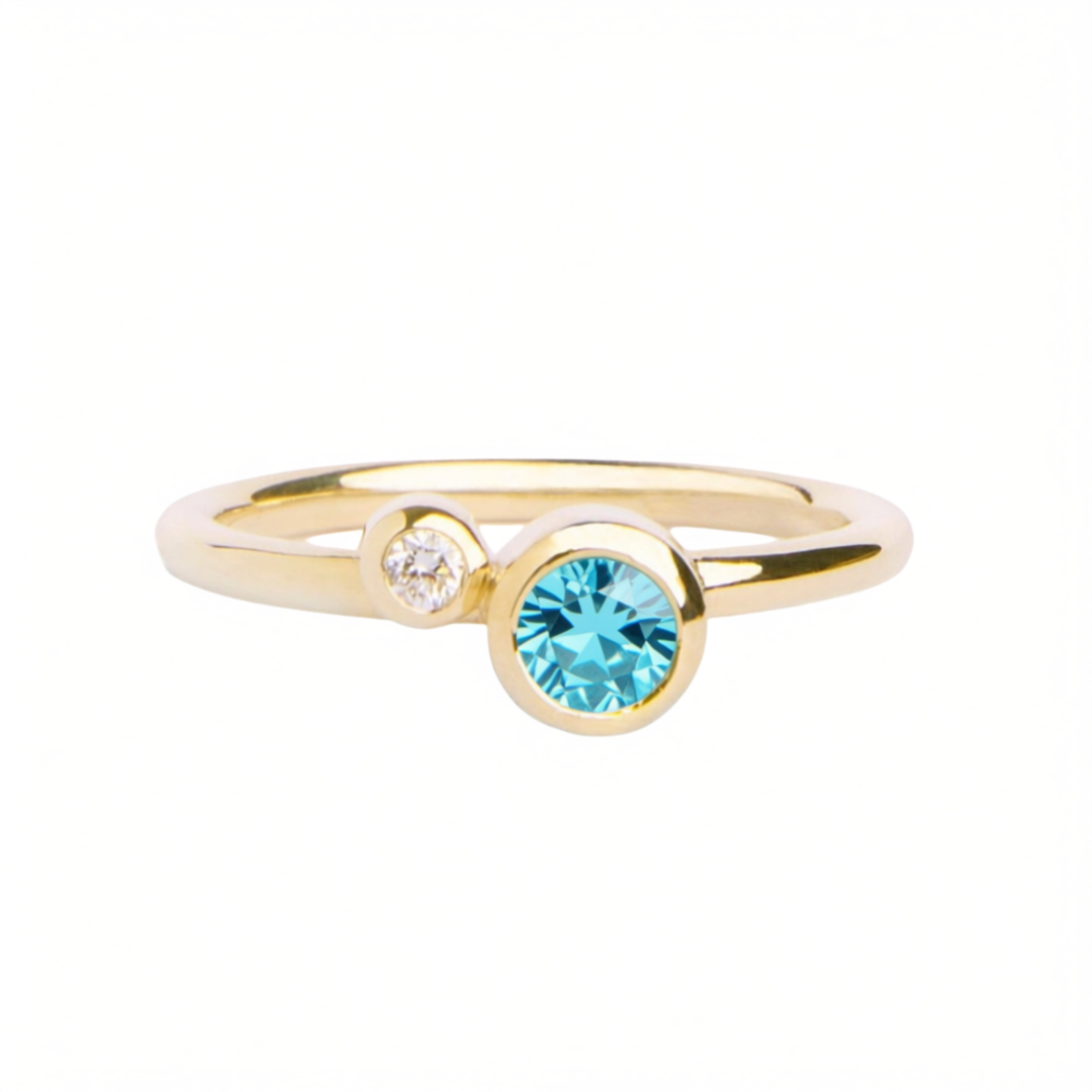 Introducing the Sky Blue Shimmer 9ct yellow gold ring by Madeleine Fine Jewellery—a nature-inspired piece featuring a dazzling round blue topaz paired with a delicate clear gemstone, both set side by side on a sleek 9ct yellow gold band.