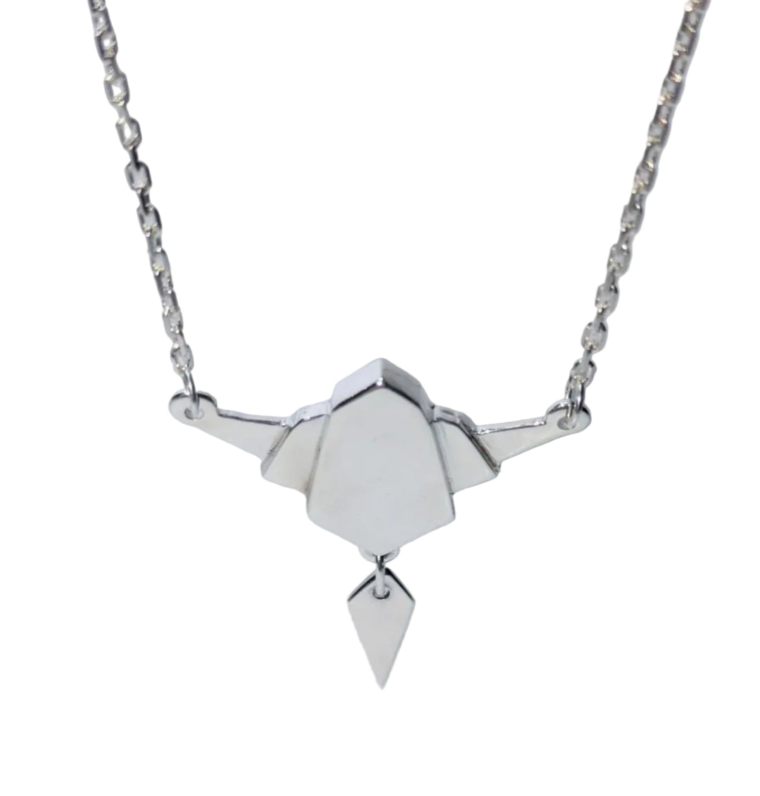The Gatsby Necklace by The Silver Rabbit features a sterling silver origami bird pendant on a delicate chain—an elegant handmade piece with its shadow cast on a light surface.