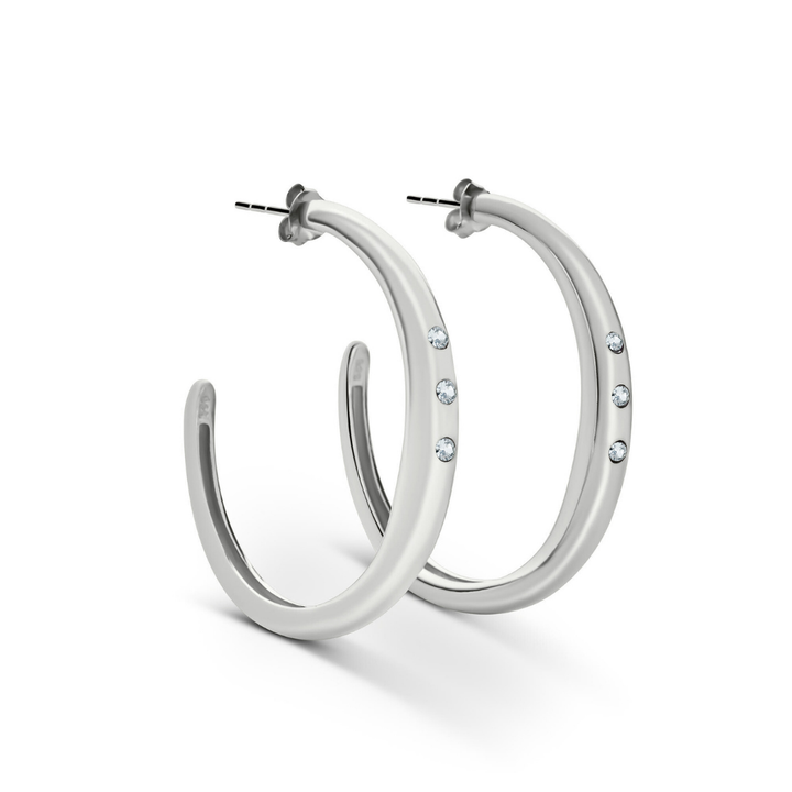 The Cualli Hoops by Gallardo & Blaine Designs are gold plated sterling silver earrings, each featuring three small round clear gemstones set along the front, shown against a plain white background.
