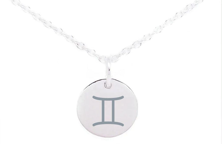 A silver necklace with a round pendant featuring the Gemini zodiac sign in the center. The pendant, showcasing sterling silver charms, is attached to a delicate, twisted chain. The background is white. This stunning piece is the "Horoscope Large Disc Charm Silver" by Personalised Charms.