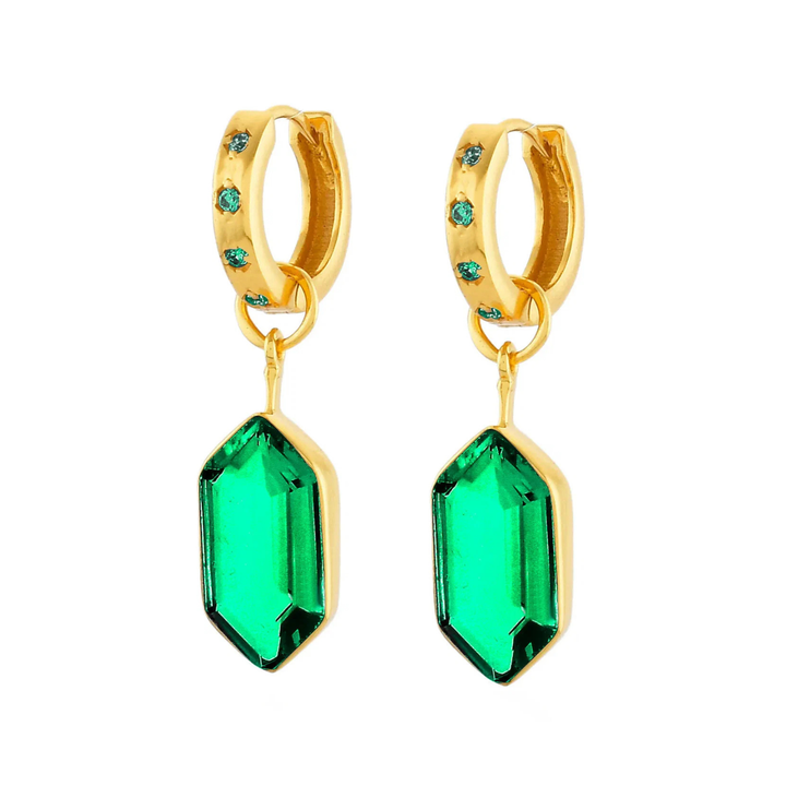 A pair of gold huggie hoop earrings with small green gemstone accents on the hoops and large faceted green gemstone dangles, shown on a plain white background.