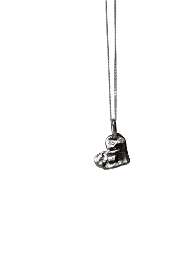 A silver pendant necklace featuring a textured, sculptural heart design, hanging from a delicate silver chain against a white background. 