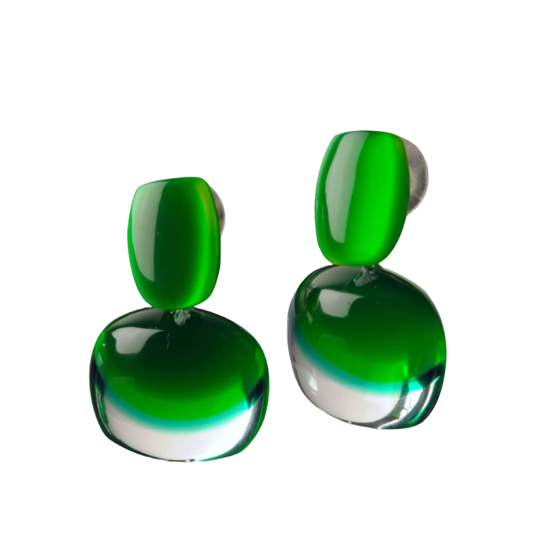 Presenting the Acrylic Green Earrings by MX.design: a pair of modern, glossy green acrylic drop earrings featuring a distinctive two-part design. The top section showcases a smaller green stone, while the bottom displays a larger green and clear stone. This elegant and contemporary accessory perfectly embodies MX.design's dedication to handmade jewelry craftsmanship.