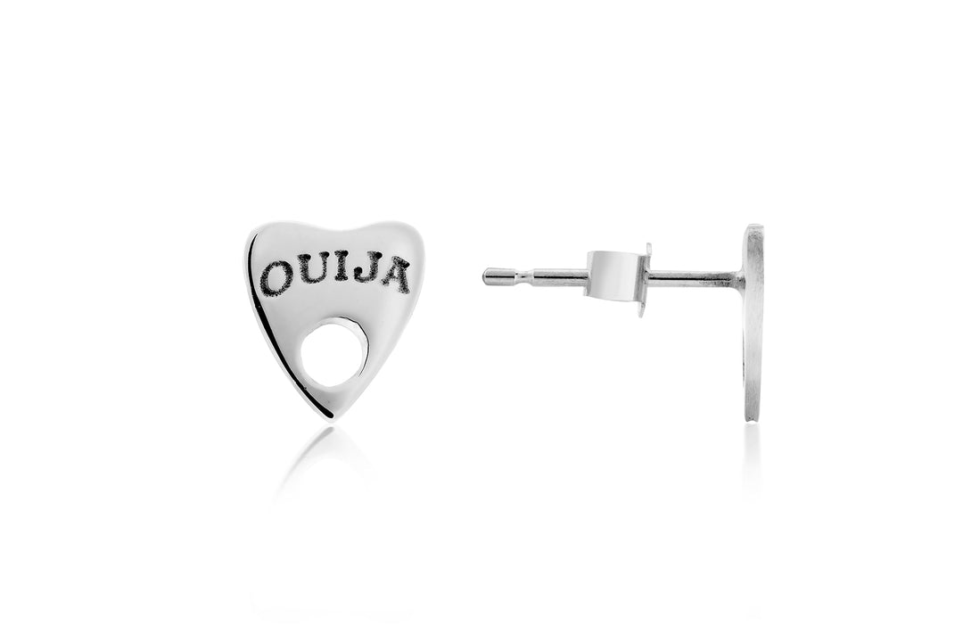 A pair of sterling silver stud earrings shaped like a heart-shaped planchette with a small round hole toward the tip. The front is engraved with "OUIJA" in all capital letters, while the back shows the post and butterfly clutch. These handcrafted, Cosmic Boulevard Ouija Silver Earrings epitomize timeless handmade jewellery.