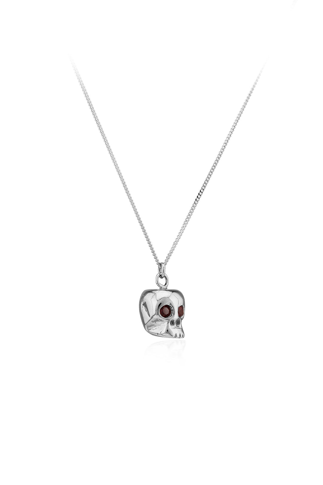 A Silver Memento Mori Skull Pendant with a pendant shaped like a skull. The skull features detailed carvings with dark, hollow eyes. Handmade jewellery from Cosmic Boulevard, this Sterling Silver Memento Mori Skull hangs elegantly on a thin chain, with the plain white background highlighting its intricate design.