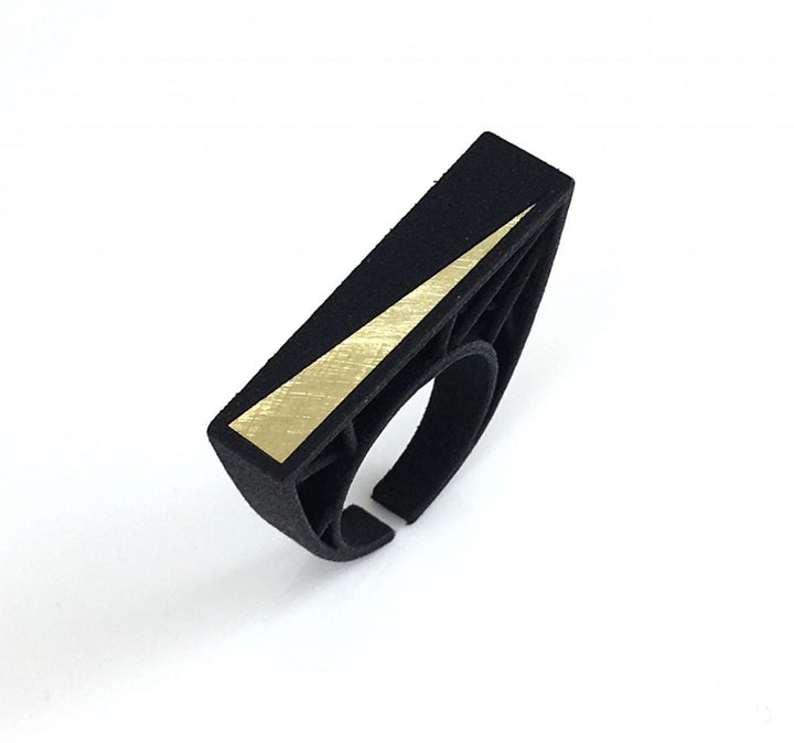 The Hebo Statement Ring by Elsiem is a modern, geometric ring crafted from SLS Nylon with a black band and a rectangular face featuring a gold diagonal stripe. The minimalist, contemporary design boasts clean lines and a matte finish. Inspired by Barbara Hepworth, the rectangular face slightly extends over the band on both sides.