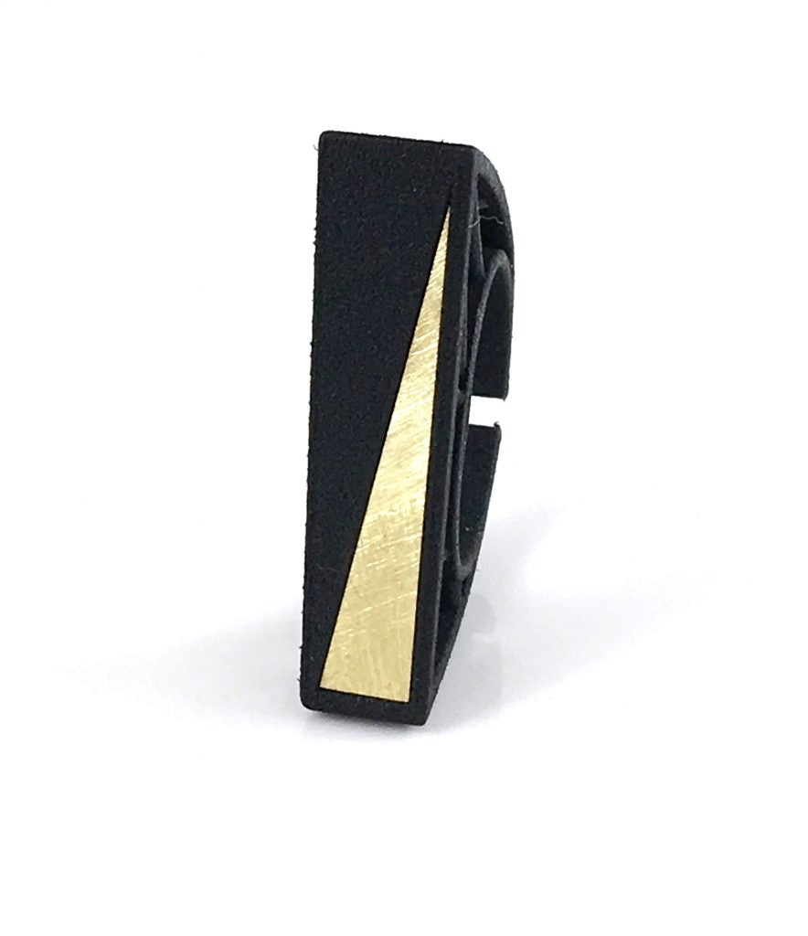 A black rectangular ring with a matte finish and a shiny, triangular gold detail on one side, reminiscent of Barbara Hepworth's sculptural elegance. The Elsiem Hebo Statement Ring stands upright against a plain white background.