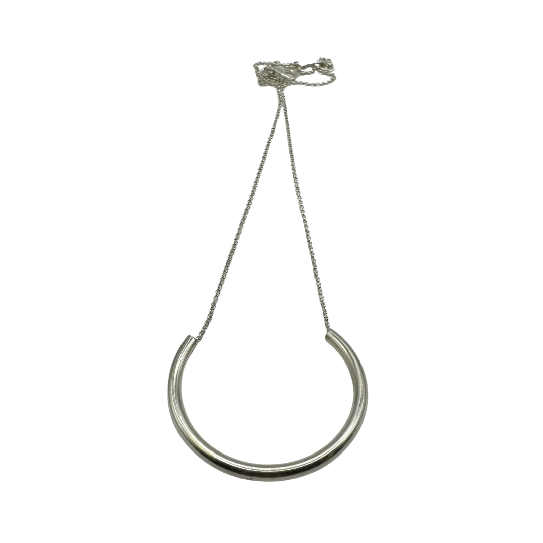 The Half Chain Necklace by Inó Jewellery features a delicate chain and smooth crescent bar pendant, shown on a white background—a refined accessory that complements handcrafted Dublin jewelry.