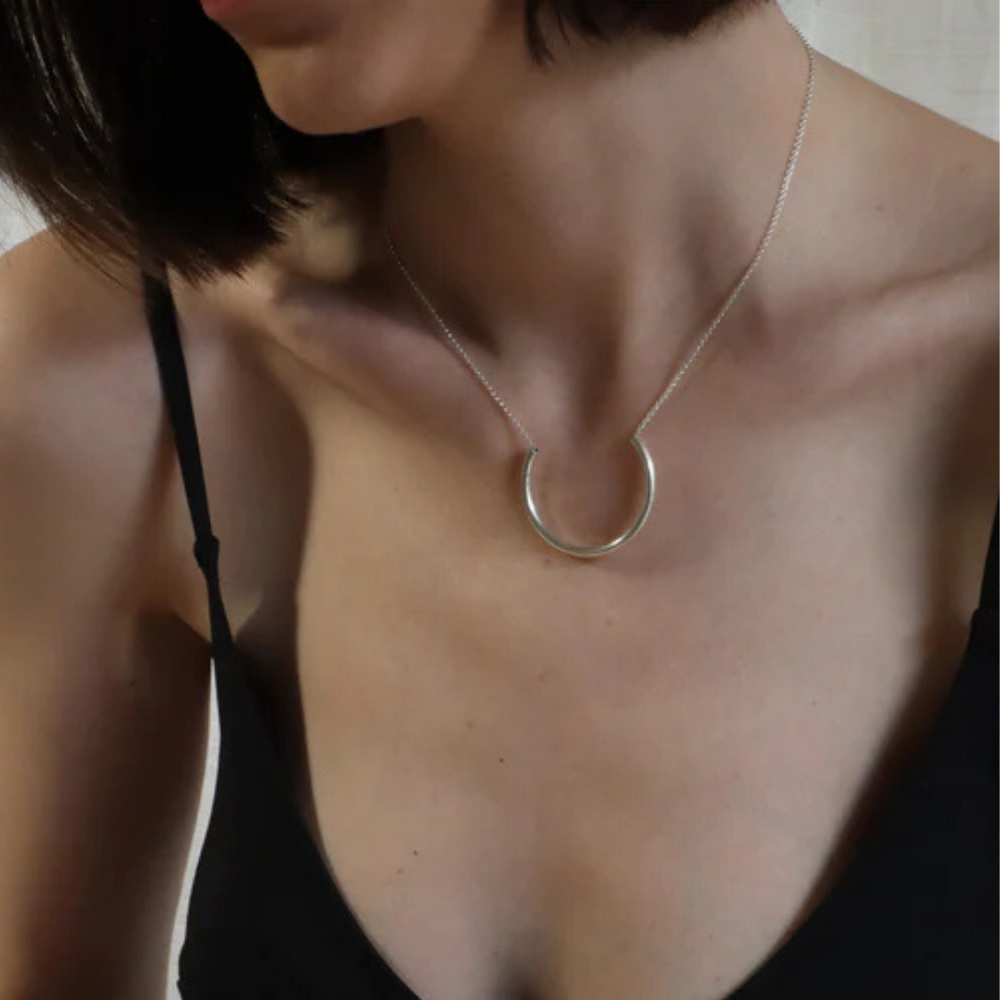 A woman models Inó Jewellery's Half Chain Necklace and a black spaghetti strap top, shown from shoulders to chest, as she turns her head slightly left.