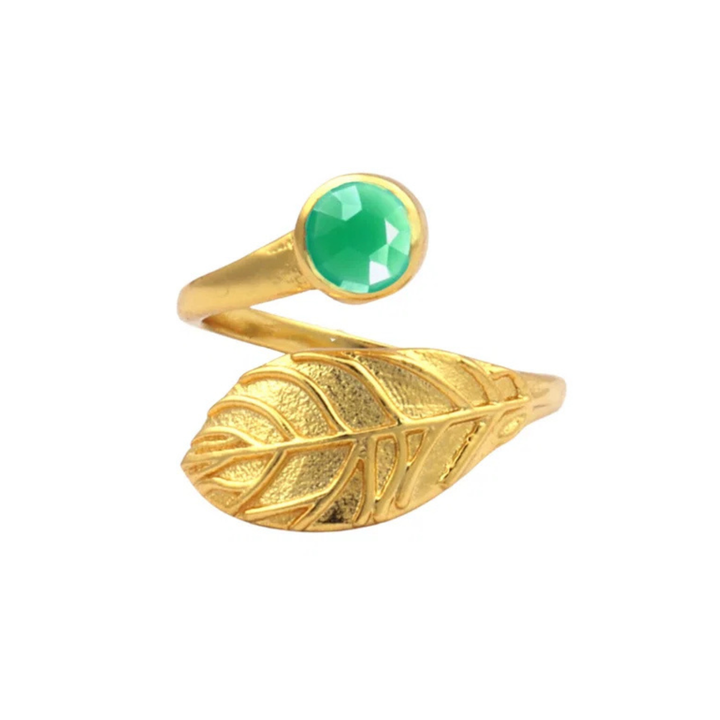 A **Hannah Gold Ring in Chrysoprase** by **Watermelon tropical** wraps around the finger. One end of the ring is designed as an intricate, detailed leaf, while the other end features a green, faceted Chrysoprase gemstone.