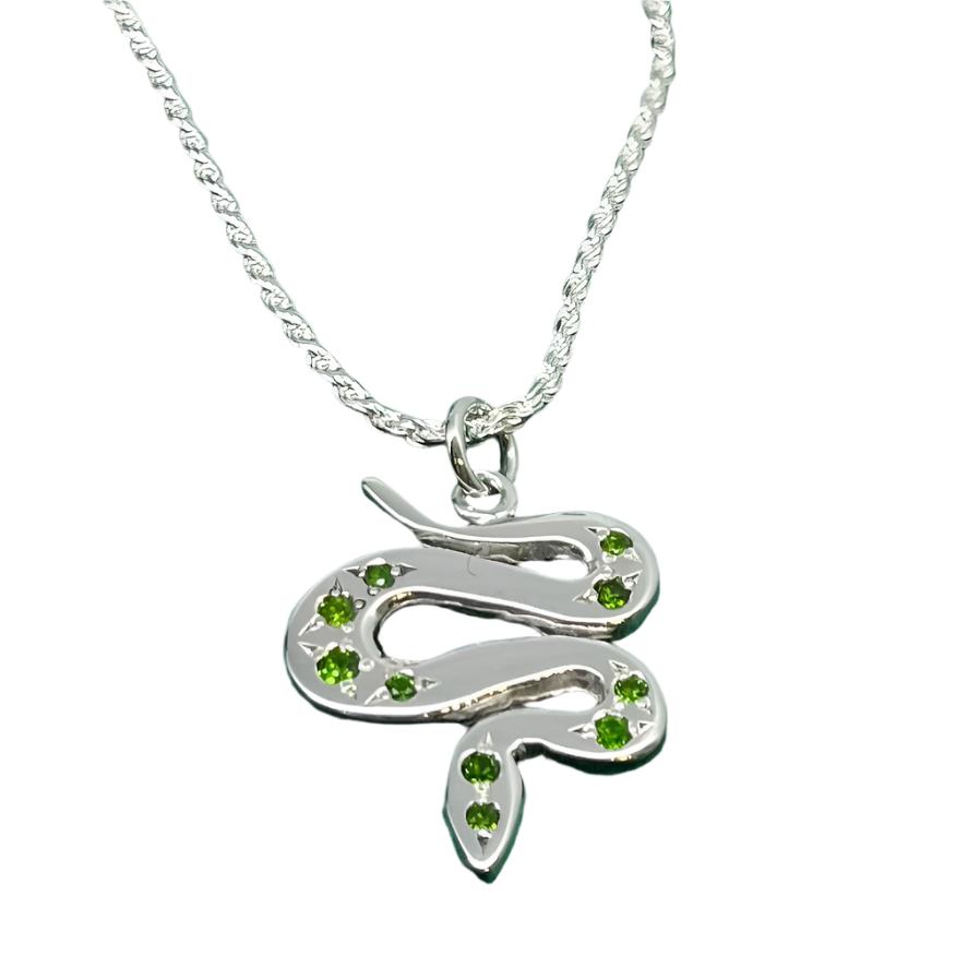 The Sterling Silver & Tsavorites or Sapphires Serpent Pendant by Cosmic Boulevard features a snake-shaped design adorned with green gemstones, showcased against a white background.