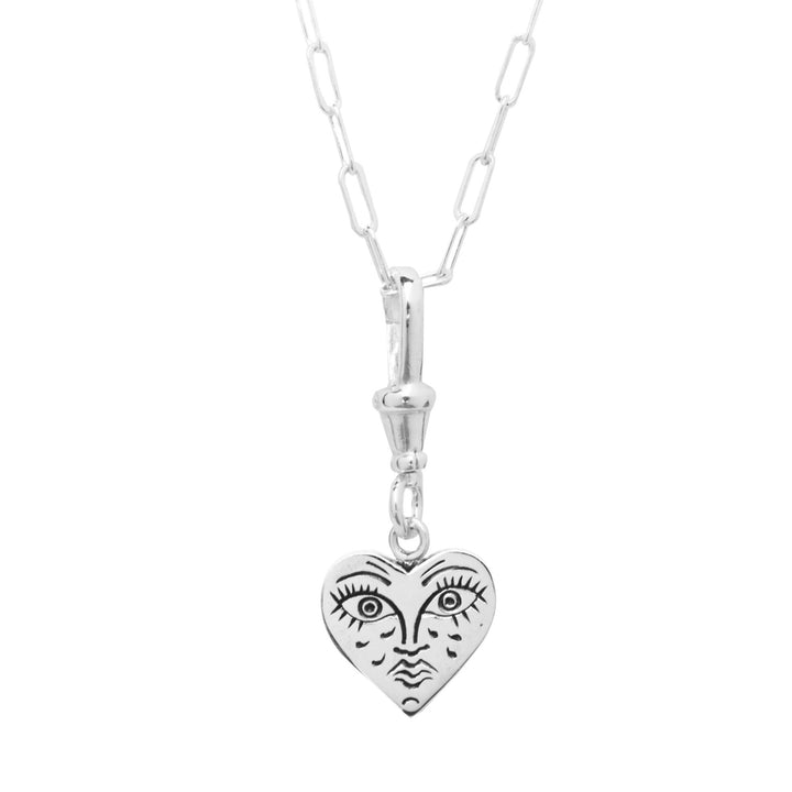 A Lil Sad Grimm Silver Pendant by Cosmic Boulevard with a unique, handmade and engraved heart-shaped pendant featuring a stylized, abstract face with closed eyes and tear marks etched into the surface. The chain consists of elongated links, giving it a contemporary look.