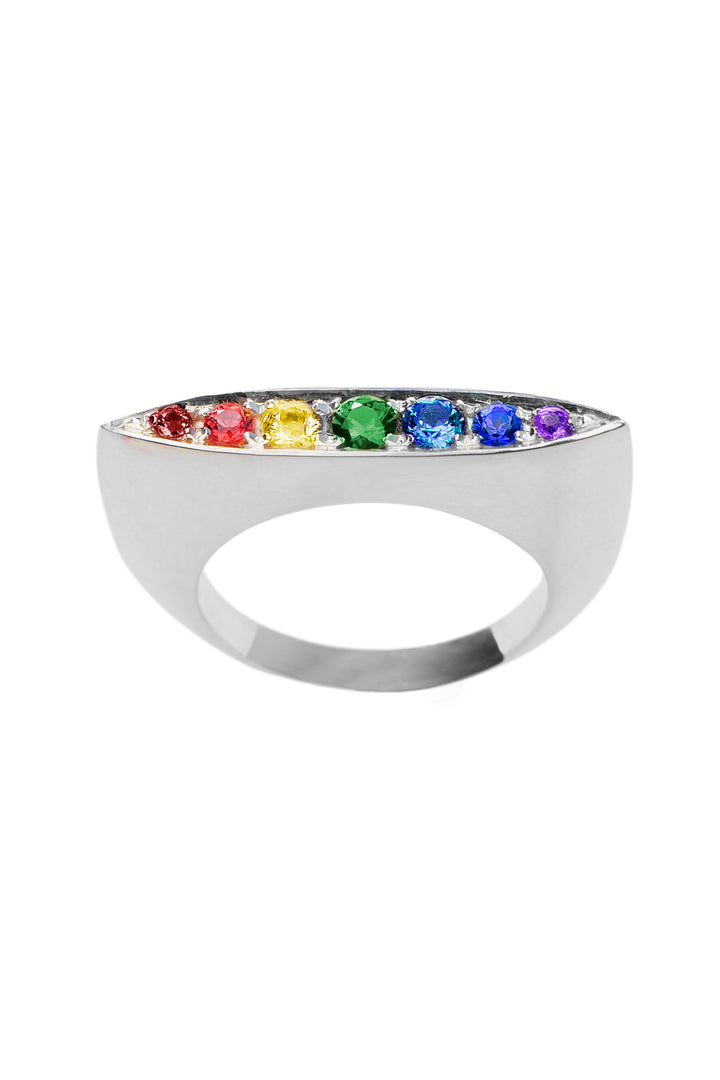 Displayed against a white background is the Rainbow Star Ring by Cosmic Boulevard. This sterling silver ring is adorned with a row of six pavé set colorful gemstones, arranged in a gradient that includes red, yellow, green, blue, and purple hues. The ring has a smooth, polished finish.