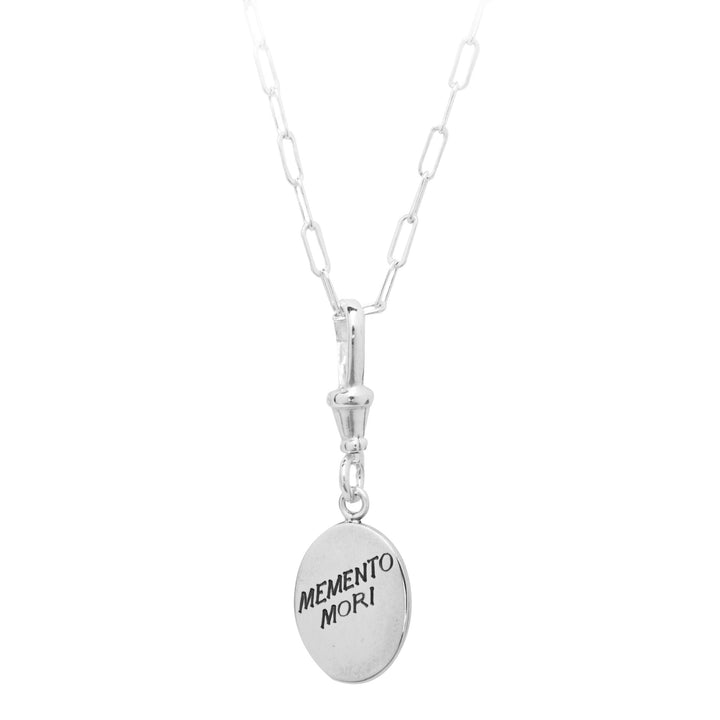 A Memento Mori Silver Pendant by Cosmic Boulevard with a chain composed of elongated, rectangular links. Hanging from the chain is a hand-engraved pendant inscribed with the Latin phrase "MEMENTO MORI," which translates to "Remember you must die.