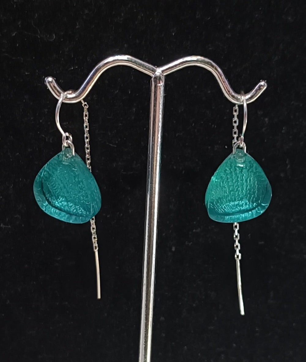 A pair of **MX.design** **Acrylic Aquamarine Earrings with Chain Back Silver** are displayed against a black backdrop on a silver stand.