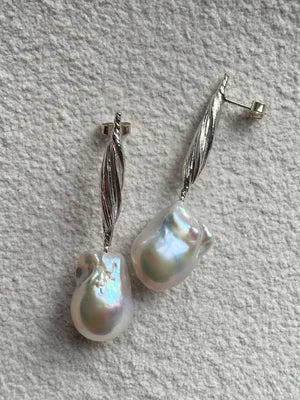 The Gathered Forms Earring with Baroque Pearls by Inner island features sterling silver leaf-shaped studs and dangling irregular white baroque pearls, displayed on a textured light gray surface.