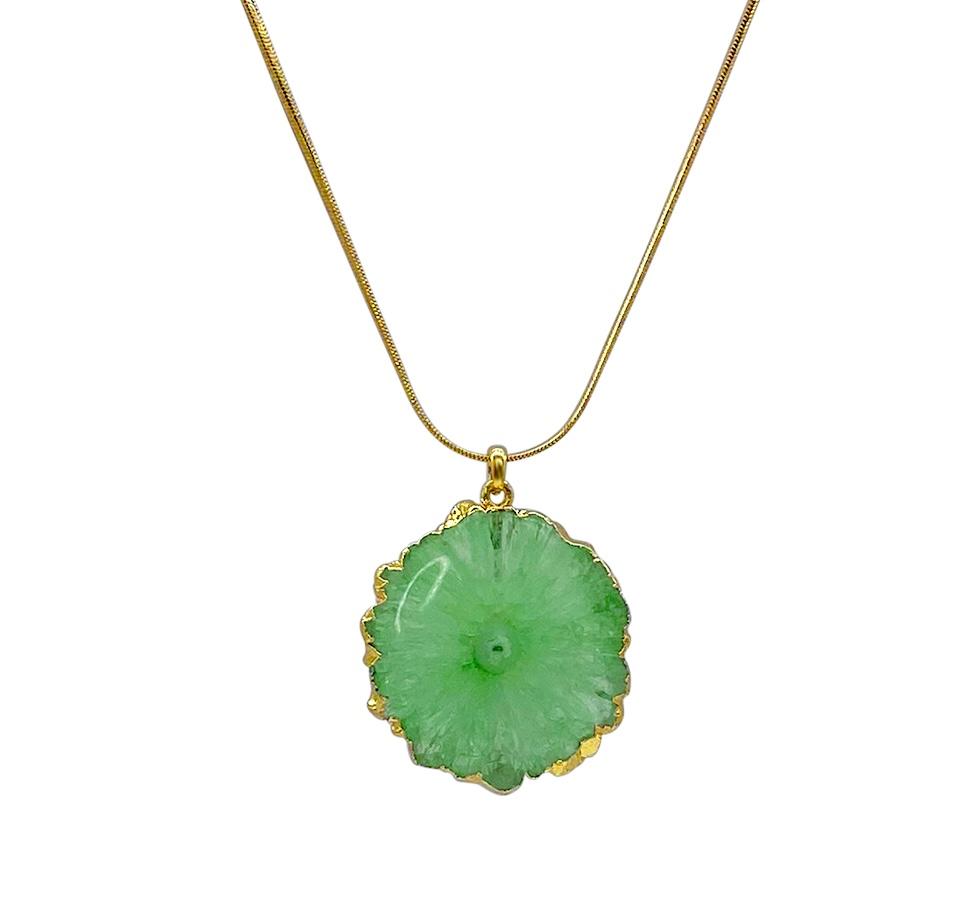 A gold plated snake chain necklace with a green Solar Agate pendant. The textured, circular pendant boasts a gold trim around the edges, resembling a blooming flower. This exquisite Aria V Geya Necklace features the pendant hanging elegantly from its center.