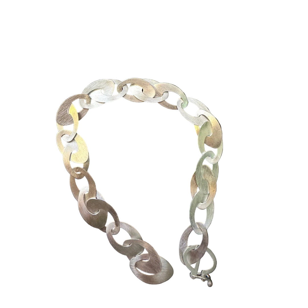 The Tezer Abstract Oval Link Bracelet features large, flat, interlocking oval links in a brushed metal finish—reminiscent of abstract oval shapes—arranged in a loose semicircle on a white background.