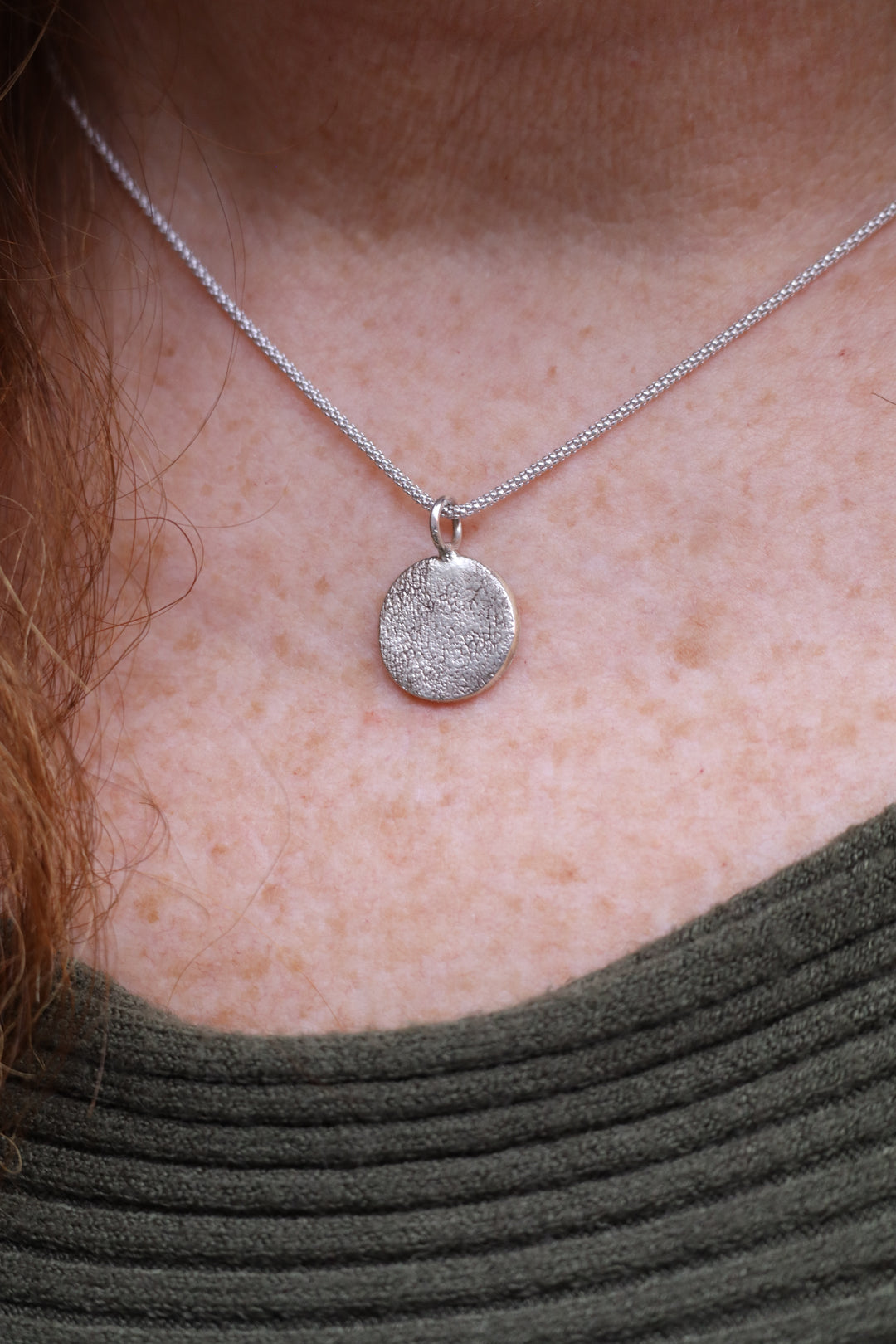 A close-up shows a person wearing the Silver Works Dog Nose Pendant Kit, featuring a textured sterling silver dog nose on a thin chain necklace, partially visible against their green ribbed top.