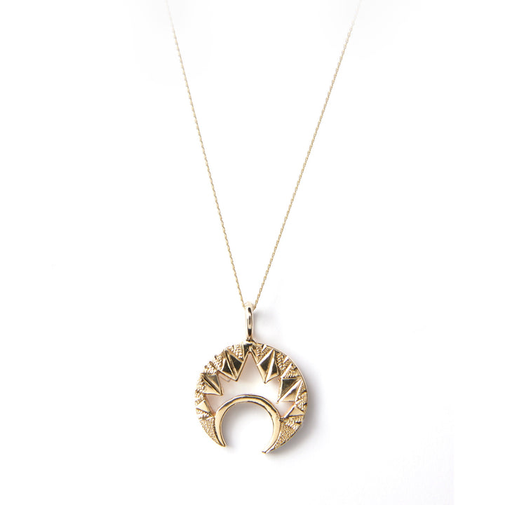 Cosmic Boulevard's "Moon & Moon" 9ct Gold Pendant features a long, thin chain in yellow gold. The pendant showcases a decorative, geometric design resembling a crescent moon encircled by triangular shapes, all hand-engraved with intricate patterns and highlighted against a white background.