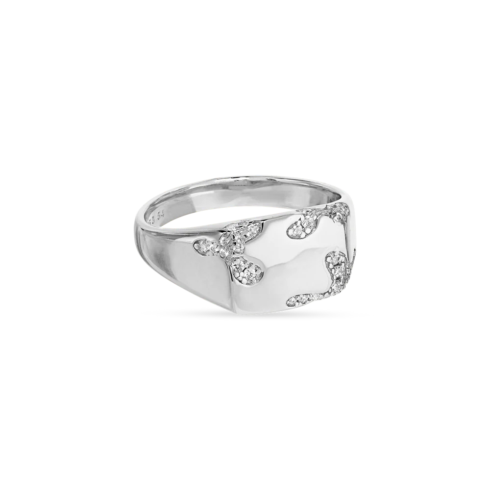 The Iced Signet Ring by Jane Koenig is crafted from 925 sterling silver with a polished finish and features sparkling gemstones in an abstract pattern, making it a striking, contemporary accessory.