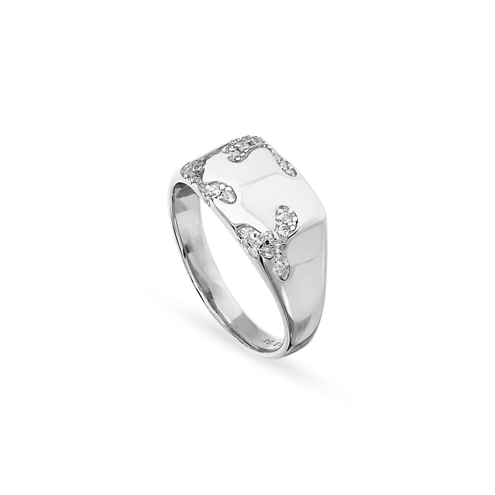 The Jane Koenig Iced Signet Ring is a 925 sterling silver ring with a rectangular top, wavy patterns, and small clear gemstones set on a polished band.