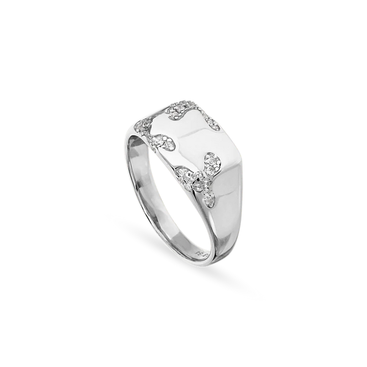 The Jane Koenig Iced Signet Ring is a 925 sterling silver ring with a rectangular top, wavy patterns, and small clear gemstones set on a polished band.
