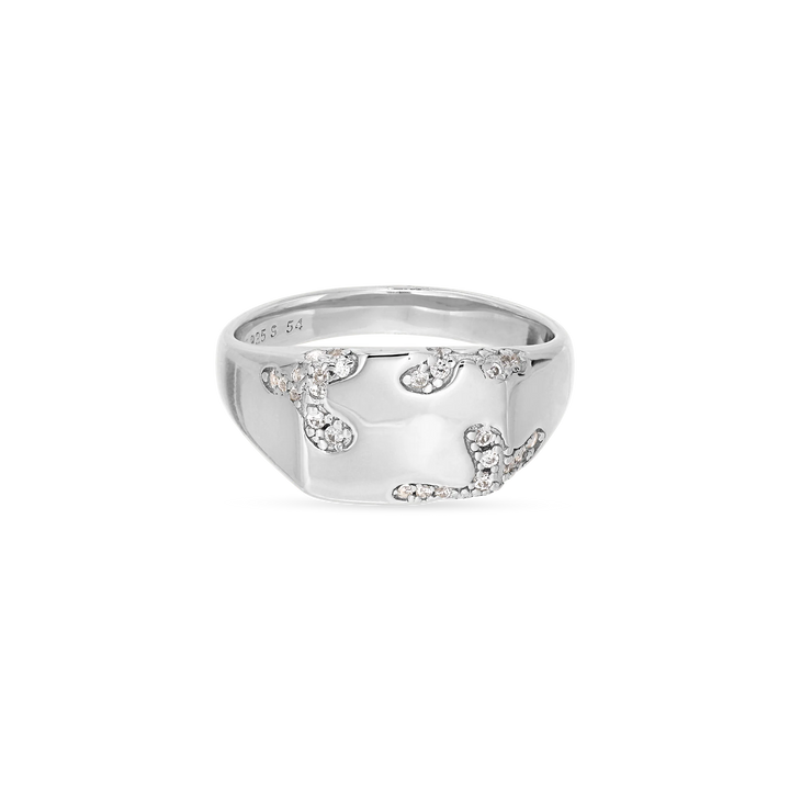 The Iced Signet Ring by Jane Koenig is crafted from 925 sterling silver and features a wide, shiny band adorned with an abstract pattern of small, sparkling white stones.