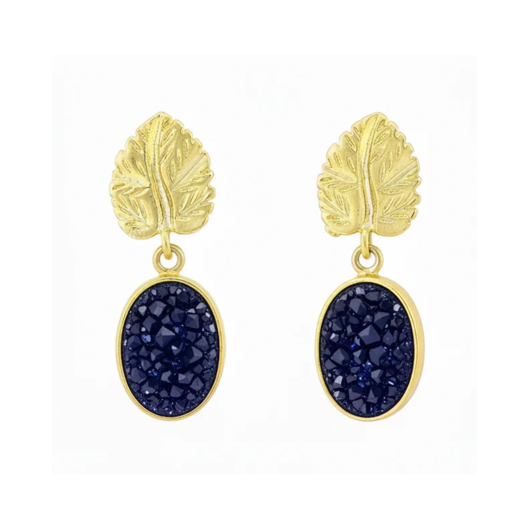 Watermelon tropical Indigo Blue Druzy And Gold Leaf Earrings feature oval indigo druzy stones set in gold plated brass with textured, leaf-shaped tops. Shown on a white background.