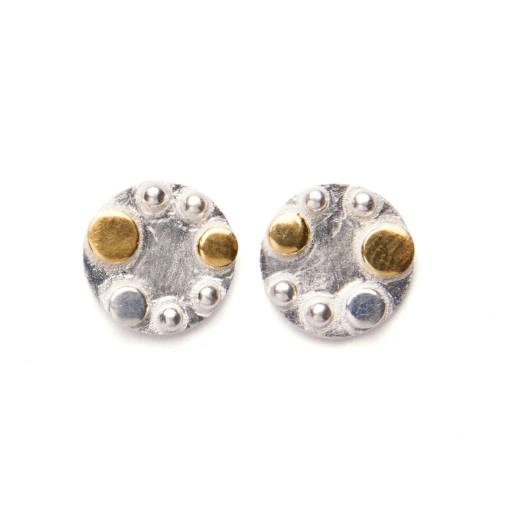 A pair of **Iona Silver & Gold Stud** earrings from **The Collective Dublin**, made of 925 Sterling silver with gold plate, adorned with small, raised details. Each earring features gold accents and silver spheres arranged in a circular pattern, giving a textured, artistic look.