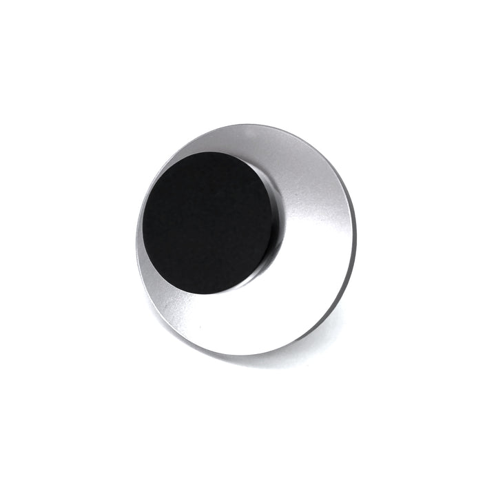 A round, metallic object with a black circular disc in the center. The outer ring is silver and reflective, creating a sleek and modern appearance. Hand-polished for a flawless finish, the Lina Ring by Alex + Svet exudes an air of elegance. It appears to be photographed against a plain white background and is viewed from a slightly tilted angle.