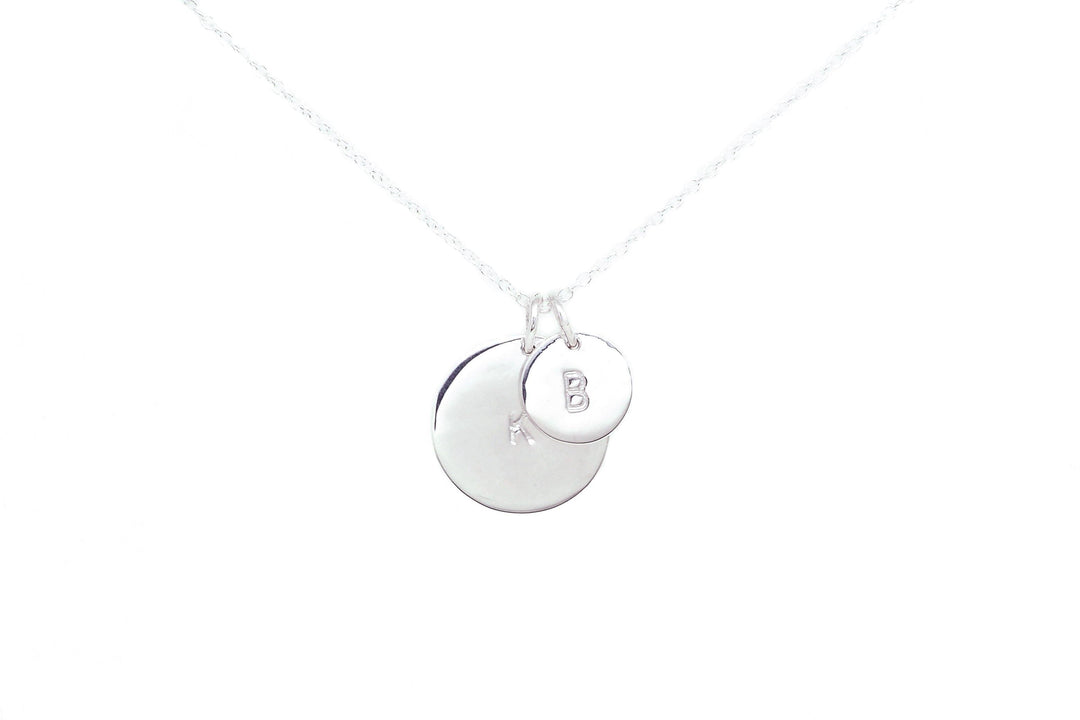 A Personalised Charms Personalised Large Disc Charm in Silver with a delicate chain features two round pendants. The larger pendant is plain, while the smaller one is hand stamped with the letter "B". This elegant piece, crafted with sterling silver charms, makes a perfect personalized gift. The background is white.