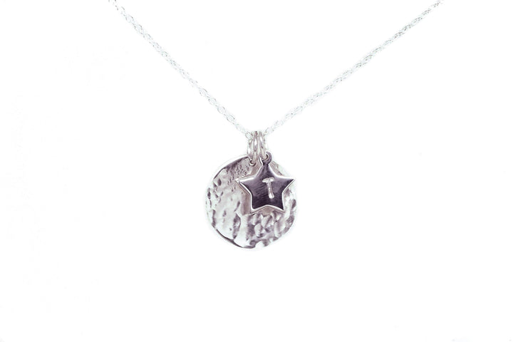 Introducing the Personalised Charms' Personalised Large Disc Charm in Silver: a delicate silver necklace featuring a round, textured pendant and a smaller star-shaped charm hanging in front of it. Both sterling silver charms are polished and shiny, with the necklace chain made of fine links. This hand-stamped piece makes a perfect personalized gift against its plain white background.