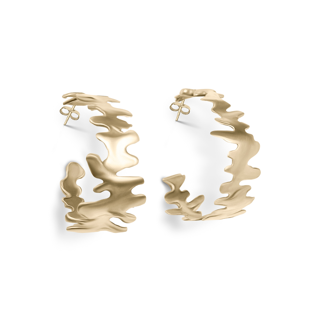The Lava Hoops by Madeleine Sculptural Jewellery are gold earrings with an abstract wavy cut-out design, crafted from recycled brass and shown on a white background.