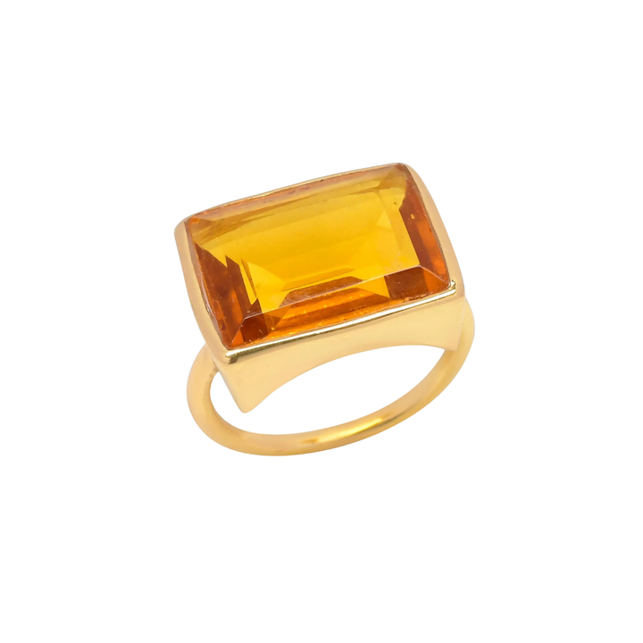 The Shyla Lenny Ring is a gold-plated cocktail ring with a large rectangular yellow gemstone in a sleek bezel setting, shown on a white background—ideal for making a bold statement.